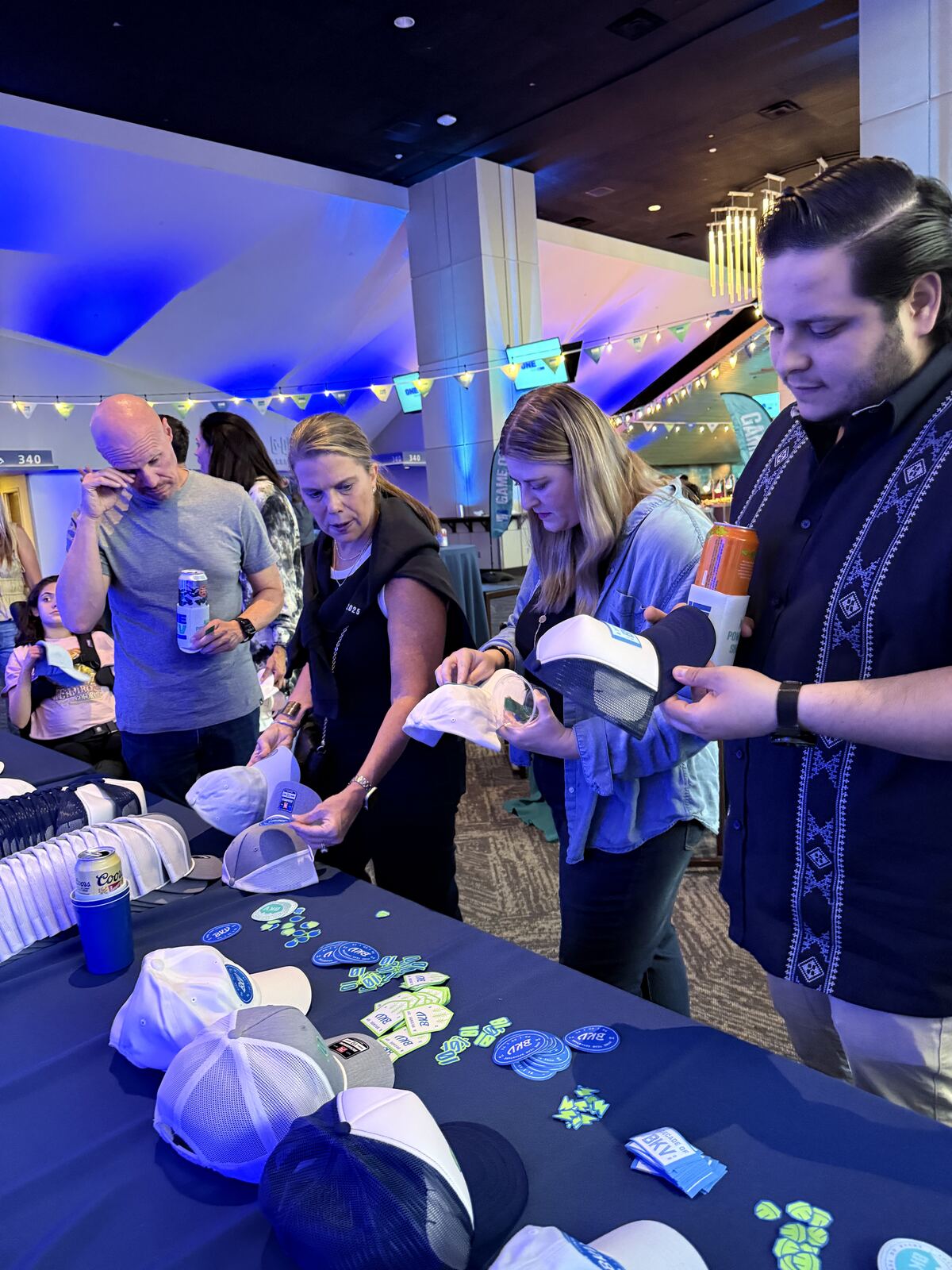 Attendees gathered at a live event booth examining custom t-shirt merchandise with decorative patches and embellishments