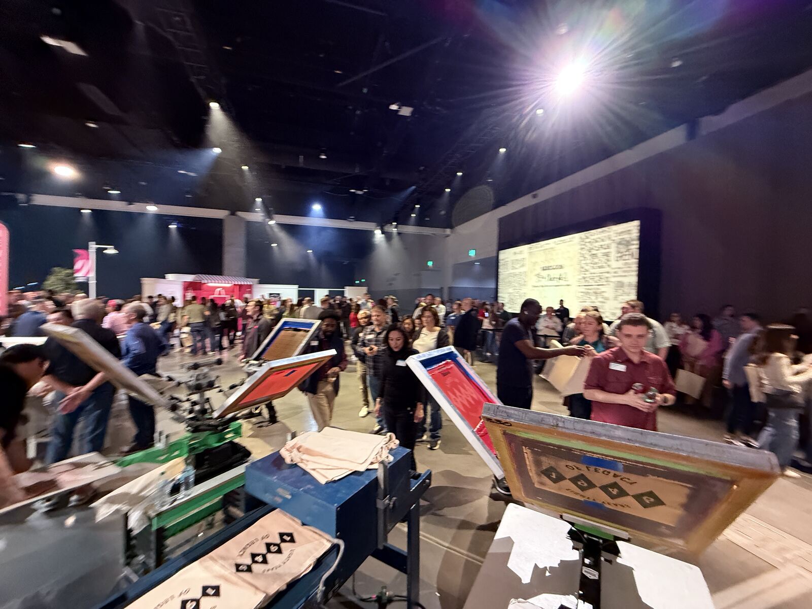 Busy event hall with multiple printing vendors and crowd of attendees examining live demonstrations