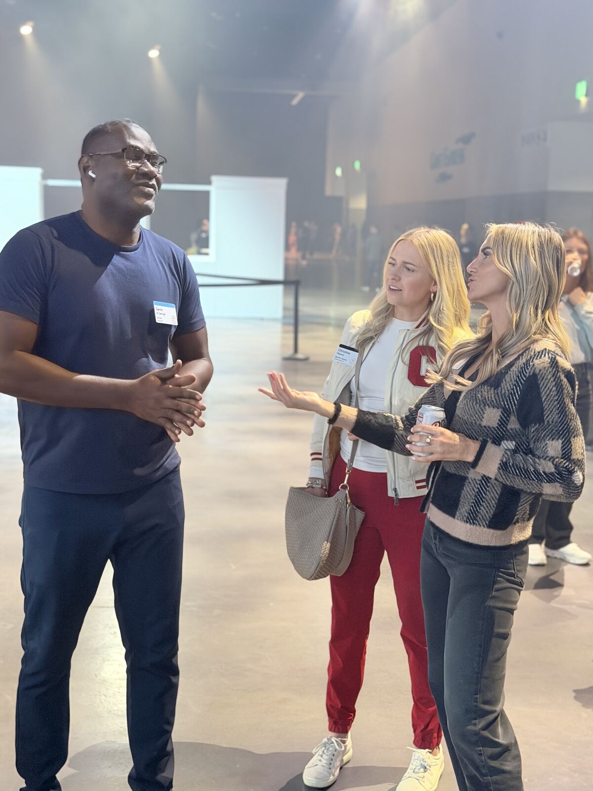 Multiple attendees at a trade show discussing with booth staff in a busy venue setting